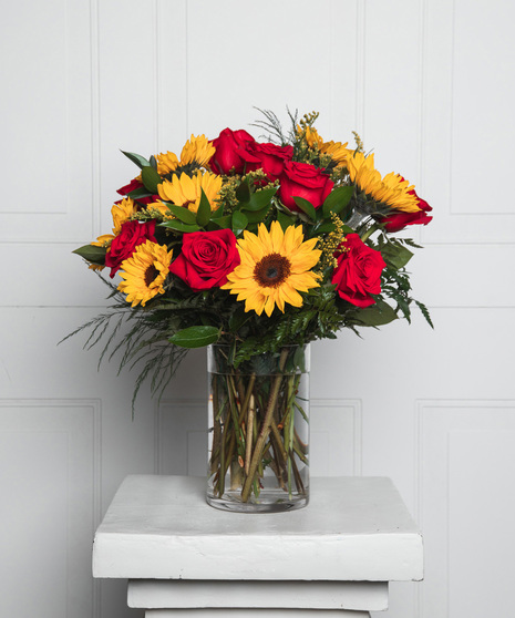 This beautiful display of floral features 9 roses in your choice of pink or red, and 8 dazzling sunflowers arranged with fresh greenery in a tapered glass vase. 