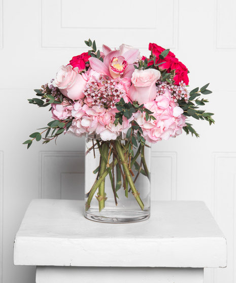 Soft pink roses, hydrangea and wax flower are hand designed in a clear vase to make the perfect opal inspired arrangement.