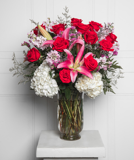 Red roses and red alstroemeria cascading upward in a Valentine's Day arrangements, paired with chocolate covered strawberries.