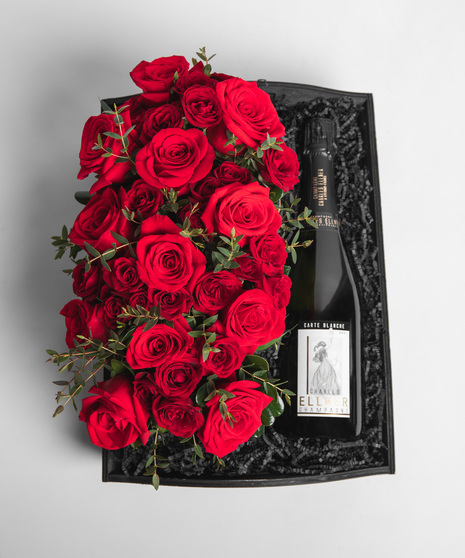 Our Prosecco or Champagn is nestled into a slate gray wooden crate with a long centerpiece-style arrangement of vibrant red roses