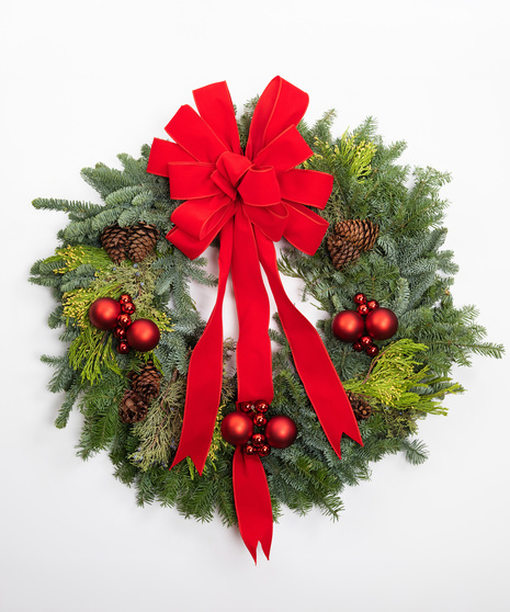 This Christmas wreath features fresh evergreen pine with accents of pinecones, cinnamon sticks, orange slices, soft bunny tails, and a burlap bow. 