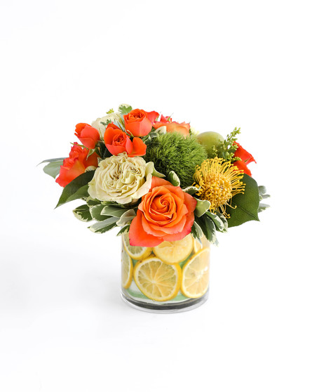 This arrangement represents our lovely sunshine state with fresh oranges, limes, yellow pin cushion protea, green tea roses, and other vibrant florals.