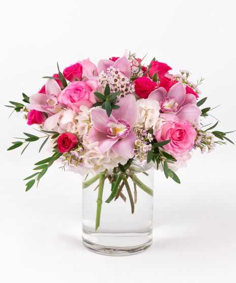 Soft pink roses, hydrangea and wax flower are hand designed in a clear vase to make the perfect opal inspired arrangement.